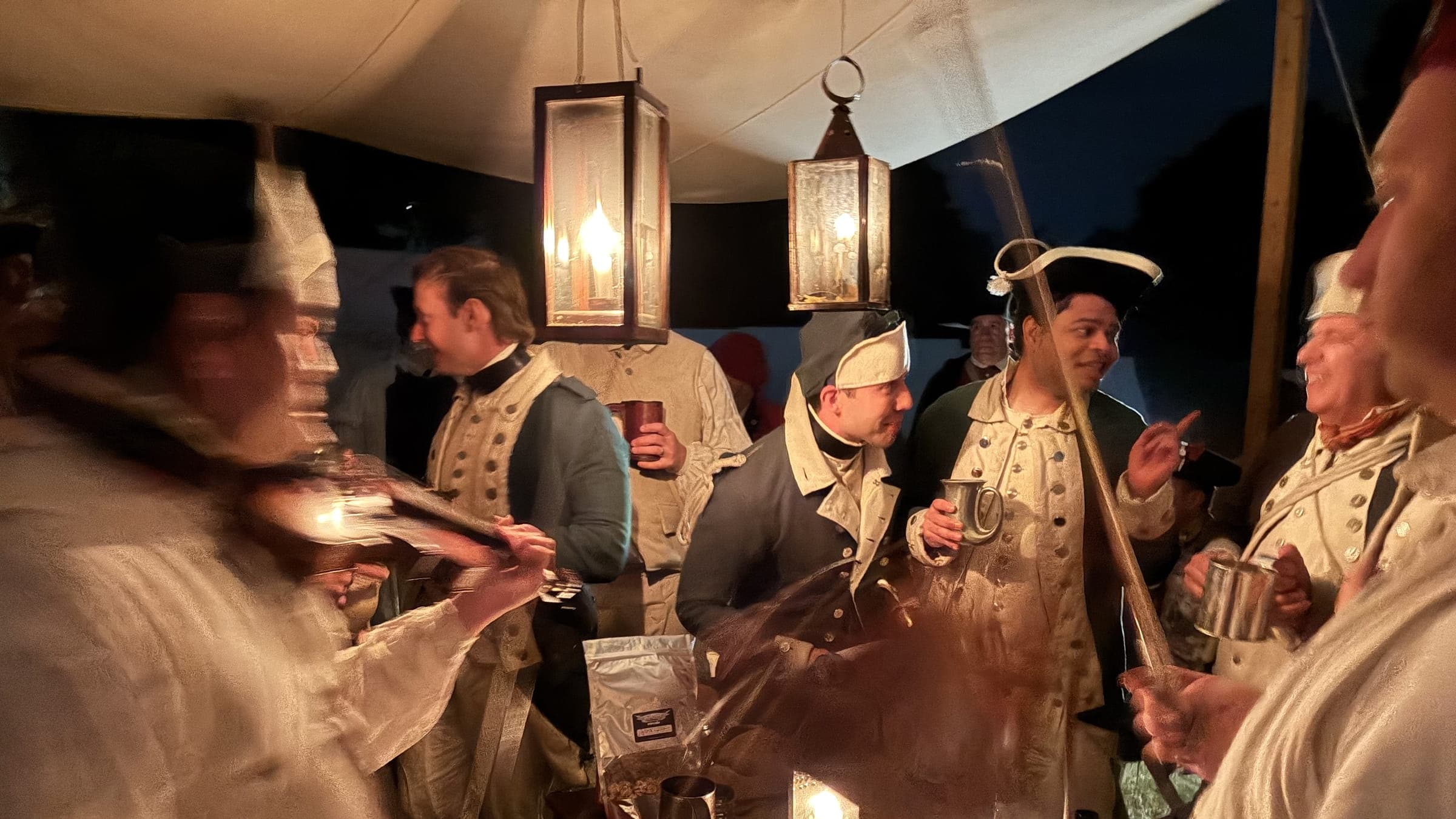 Revolutionary War soldiers socializing in a tent at night.
